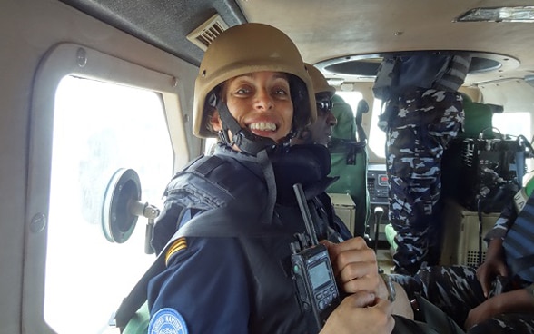  A woman police officer inside a moving armoured vehicle wearing a helmet and a walkie-talkie