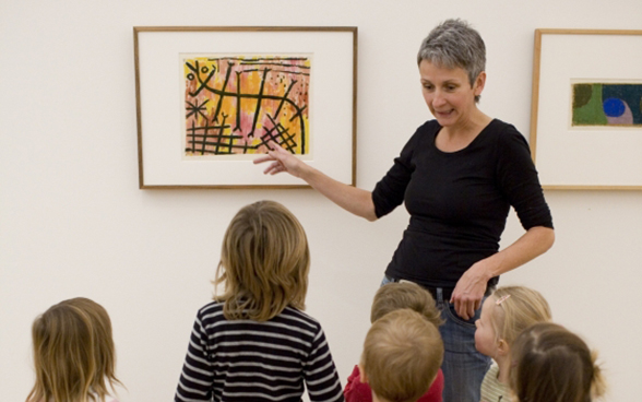 Eine Frau erklärt einer Gruppe Kindern ein Gemälde