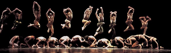 舞台上で跳ね上がり、様々なポーズをとるバレエダンサーの列