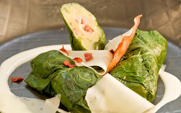 用甜菜叶包裹奶油面团和肉丁制成的菜卷Capuns。 