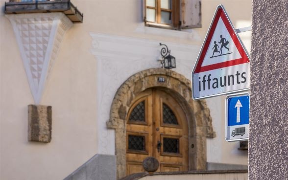 Road sign in Romansh indicating a school in the commune of Zuoz, canton of Graubünden. 