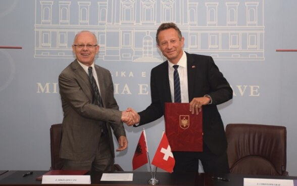 Ministri i Financave të Shqipërisë Shkëlqim Cani duke shtrënguar duart me Ambasadorin zviceran Christoph Graf pas nënshkrimit të marrëveshjes mbi menaxhimin e borxhit public.