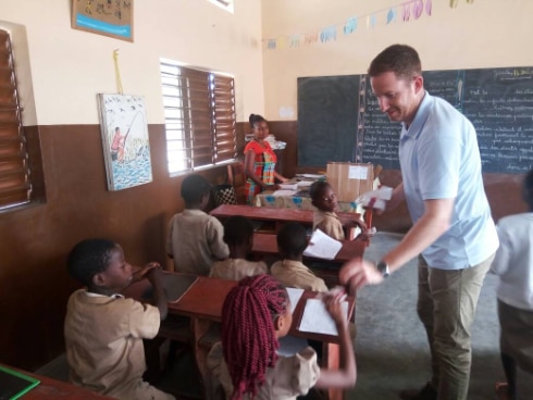 Le chef domaine gouvernance, Sylvain Corderoy remettant une boîte de crayons à une écolière 