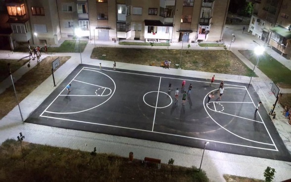 Un gruppo di giovani gioca su un campo di basket illuminato.