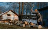 Woman cutting woods in front of her house in the woods