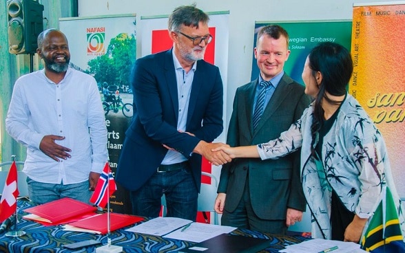 Head of International Cooperation at the Embassy of Switzerland in Tanzania Mr. Leo Nascher shakes hands with Nafasi Art Space Director Ms. Rebecca Mzengi Corey at a press event. Looking on is the Nafasi Board Chair Paul Ndunguru (far left) and the Head of Cooperation at the Royal Norwegian Embassy in Tanzania Mr. Kjetil Schie.  