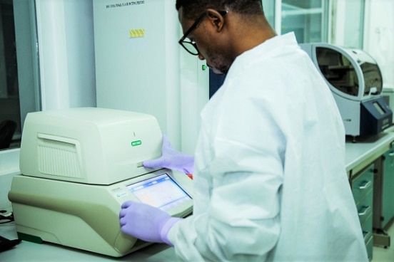 A lab technician at a IHI laboratory in Bagamoyo operating a PCR machine.