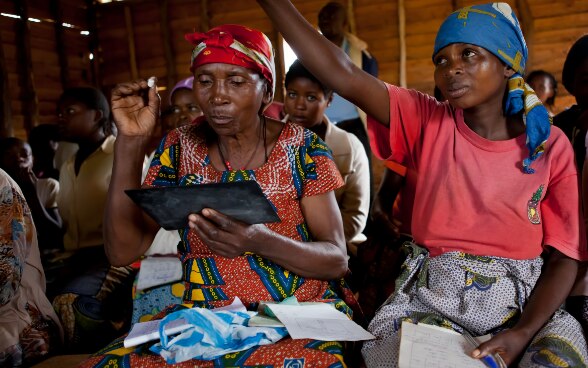 Femmes assises en classe et levant la main pour poser une question.