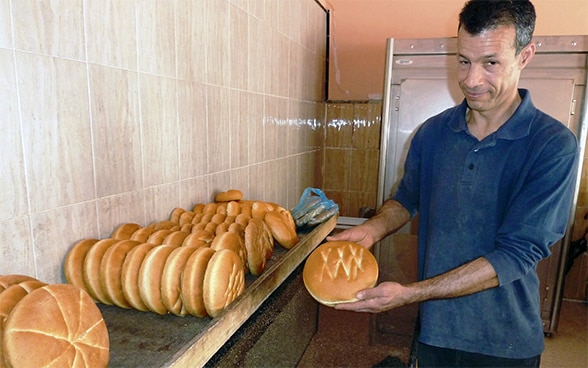 Ein Bäcker zeigt frisch gebackene Brote.