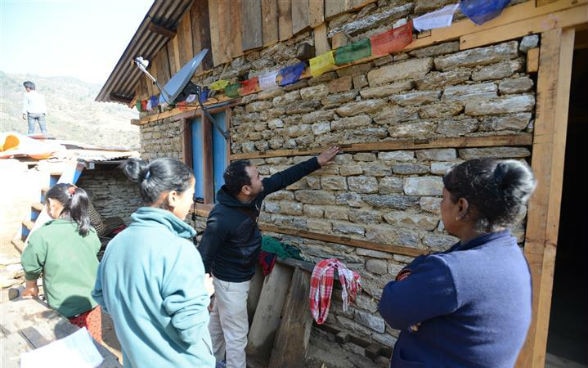 A builder talks to local women in front of their house