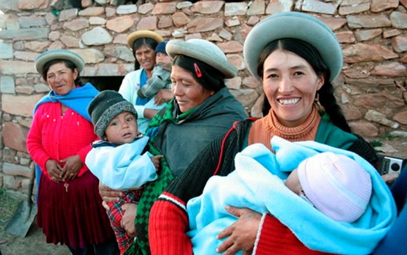 Quattro donne boliviane; tre di loro tengono in braccio un bebè.