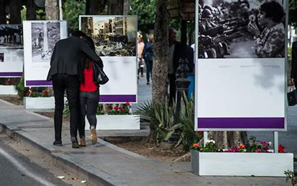 Una coppia passeggia lungo l’Avenue accanto alle fotografie di Making Peace.