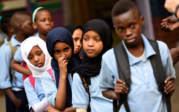 Enfants et adolescents de diverses nations attendent en file indienne.