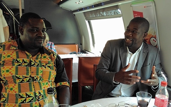 Ambroise Tapsoba und Issa Compaoré unterhalten sich an einem Tisch in einem Speisewagen der SBB.