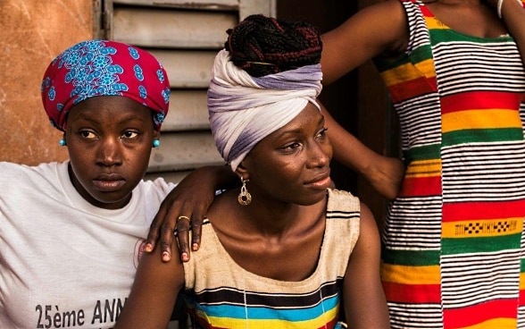 Trois jeunes femmes maliennes avec des habits colorés regardent l’horizon