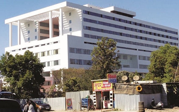 L'hôpital de Pune est un grand bâtiment blanc entouré d'arbres. Au premier plan, des baraquements en bois.