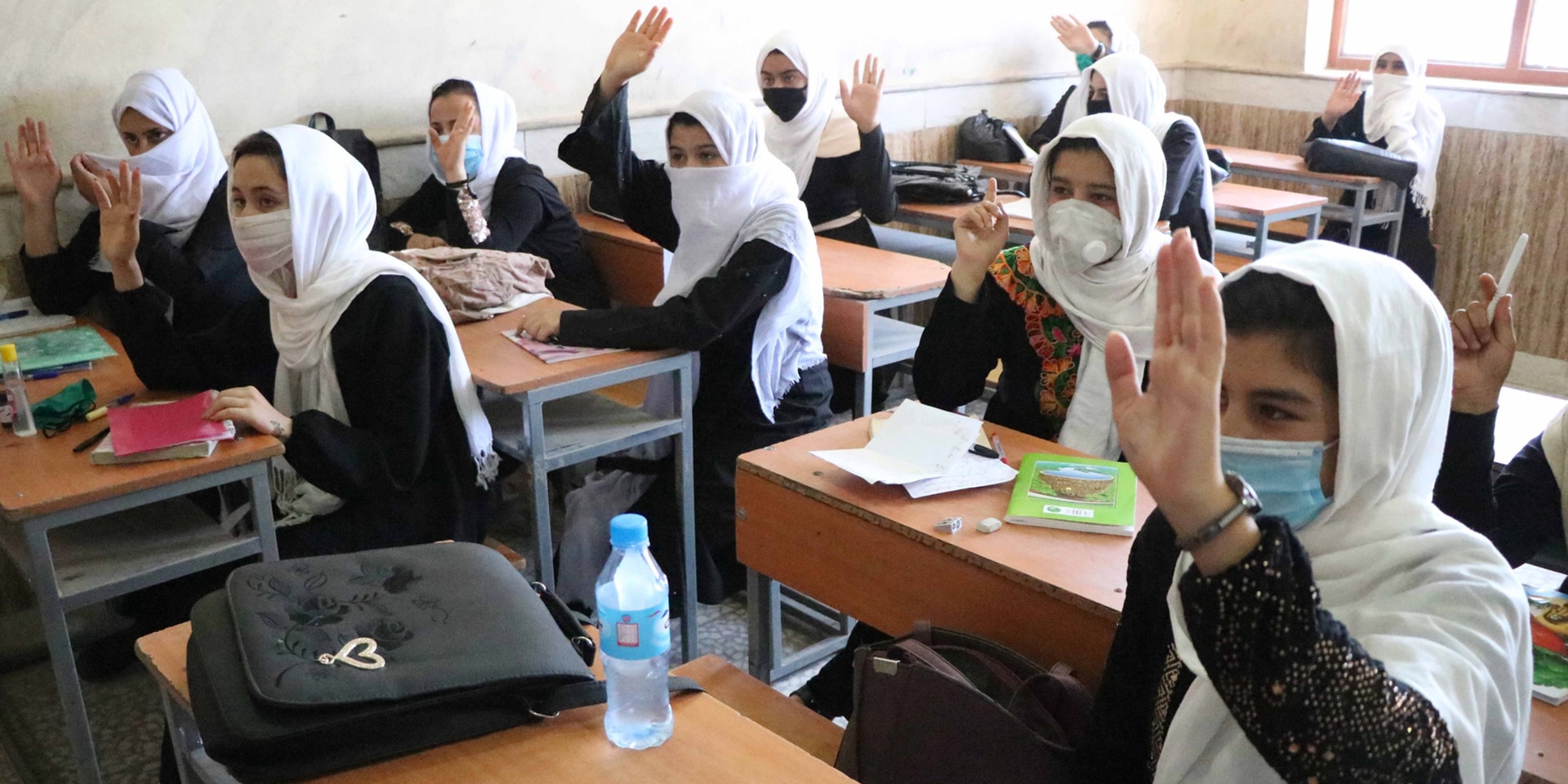 Ein Klassenzimmer in Afghanistan mit Mädchen, die die Hand heben, um eine Antwort zu geben.
