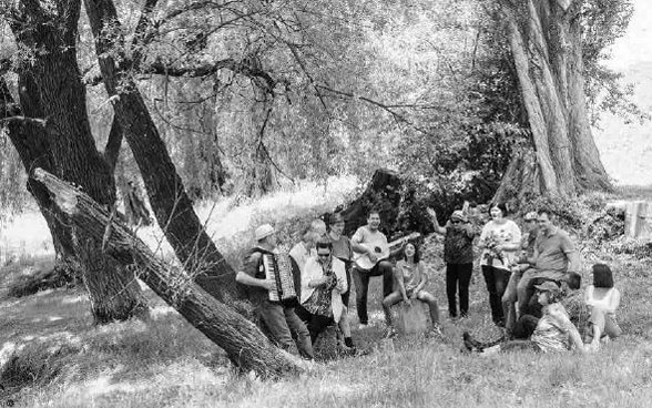 Gruppe macht in einer Waldlichtung gemeinsam Musik.