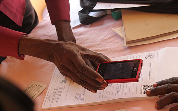 Una donna scansiona con il cellulare un codice QR stampato su un foglio.