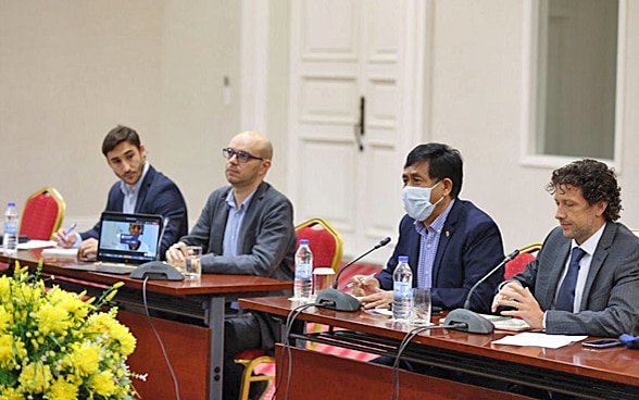 Dos representantes de la COSUDE y dos de la ONG People in Need están sentados en una mesa. Explican su proyecto a los representantes del gobierno camboyano.