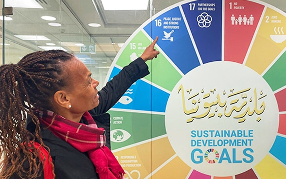 Patricia Danzi points to one of the 17 UN Sustainable Development Goals on a circle board.