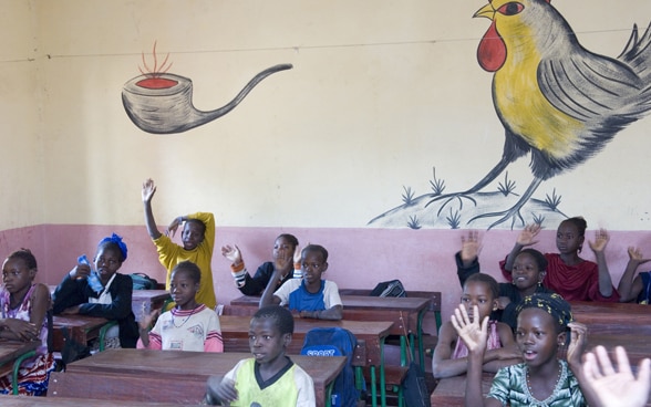 School class in Mali in front of a brightly painted wall.