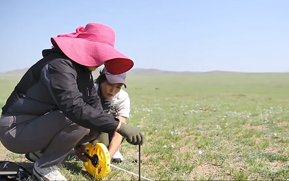 Zwei Frauen nehmen auf einem Feld Messungen vor.