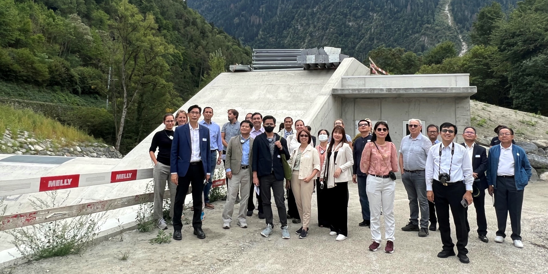 Die beiden asiatischen Delegationen posieren vor einem Staudamm in Martigny.