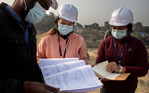 Deux jeunes ingénieures examinent un plan sur un chantier.