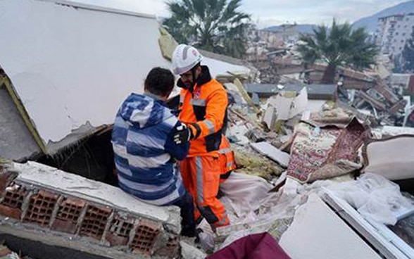 A member of Swiss Rescue talking to a person in the ruins of a collapsed house.