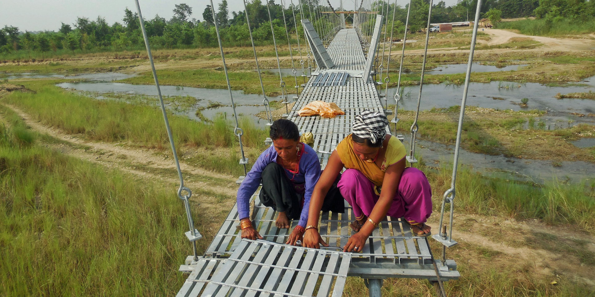 Mujeres montan los elementos del suelo del puente de Ghurswaghat, en Kanchanpur.