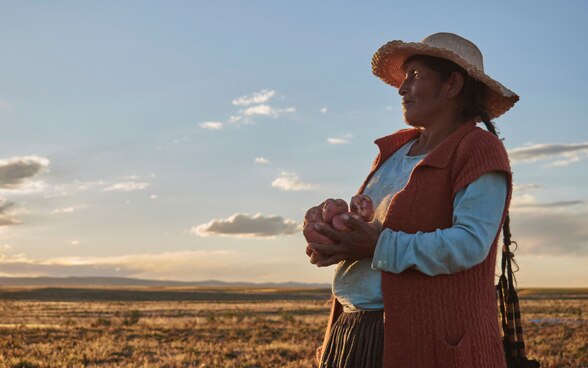 Bolivian farmer holds potatoes in her hands.