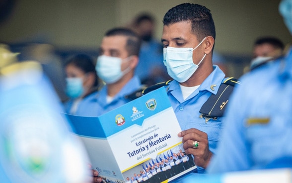 A Honduran policeman studies a brochure.