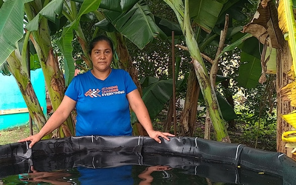 A Nicaraguan farmer in front of her water reservoir.