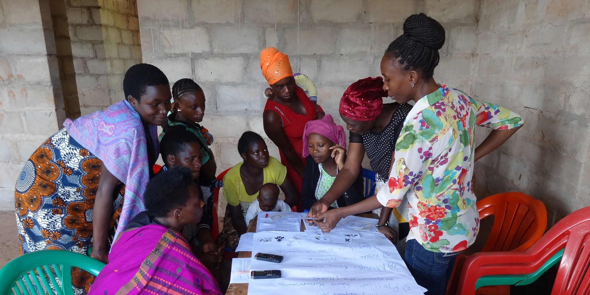 Un gruppo di donne lavora a un tavolo in Tanzania. Sul tavolo sono disposti dei fogli.