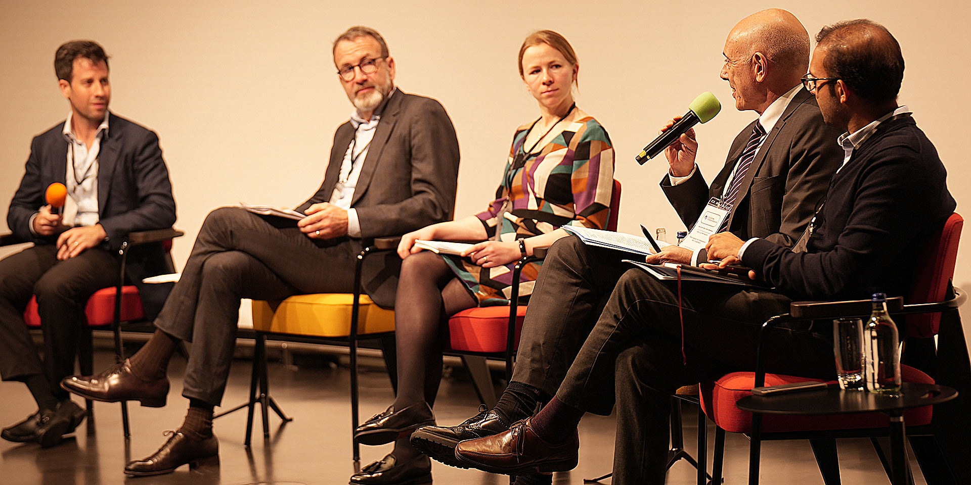 One woman and four men sitting on stage for a panel discussion.