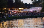 Représentation de théâtre avec éclairage sur les rives du lac de Zurich à la tombée de la nuit.