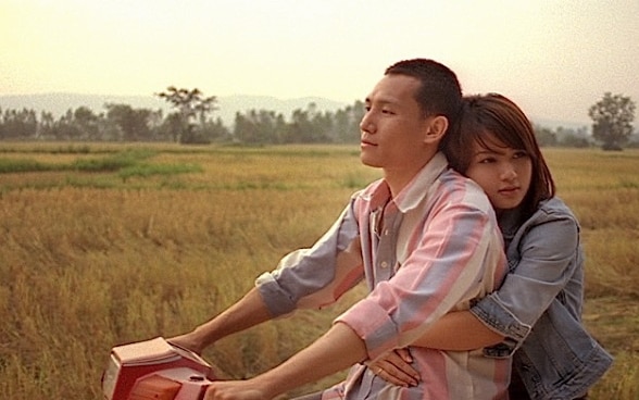 Un uomo e una donna abbracciati su un motorino.