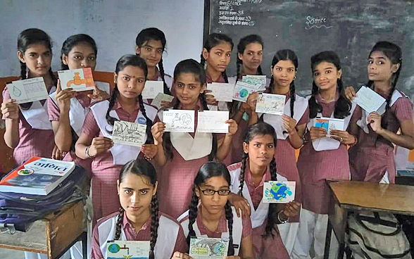 Una classe di bambine in India mostra con orgoglio le cartoline disegnate e scritte a mano che verranno utilizzate per stabilire il record mondiale sullo Jungfraujoch.