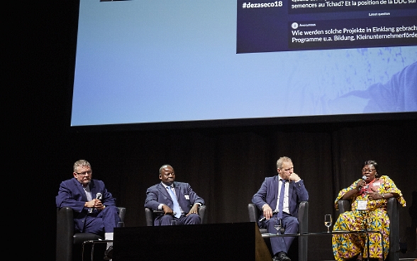 Mansour N’Diaye, Dominique Guenat, Pierre-André Page, Mariane Nguerassem et la modératrice Melanie Pfändler sont assis sur la scène. En arrière-plan, on voit le Power Point sur lequel sont affichées les questions du public.