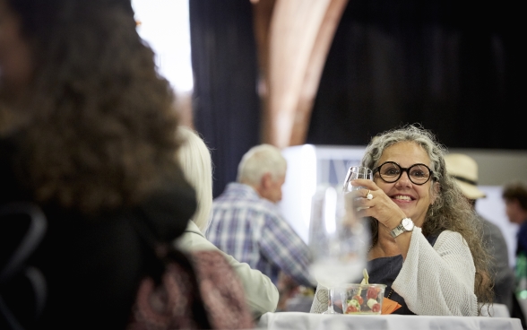 Une participante souriante à une table avec un verre d’eau dans la main.