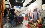 An SDC employee chats to a young woman against a backdrop depicting life in Peru. 