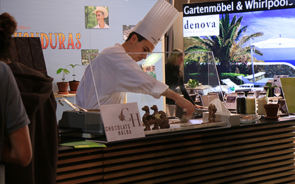 Ein Mann giesst am Stand zum Land Honduras an der DEZA-Sonderschau an der OLMA 2015 Schokolade. 