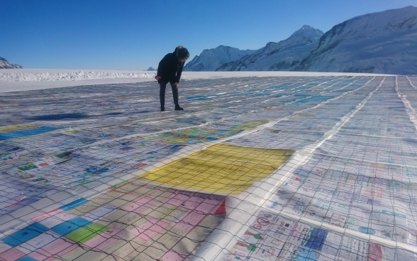 Une femme contemple la mosaïque de cartes postales disposées sur un glacier.