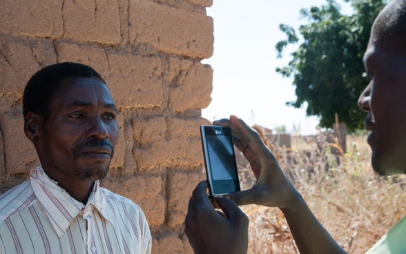 Un uomo africano di una regione rurale viene registrato nel sistema di assicurazione sociale mediante un telefono cellulare.
