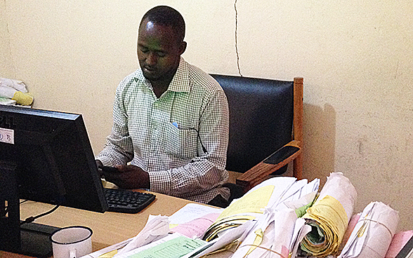 Sitting at his desk, a Hargeisa municipal employee enters paid bill details into a computer system.