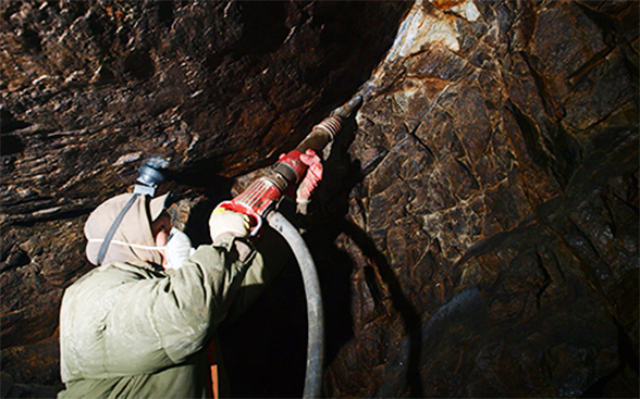 Un minatore fora la roccia alla ricerca d’oro.