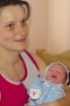 Eine Mutter hält ihr Neugeborenes lächelnd auf dem Arm.