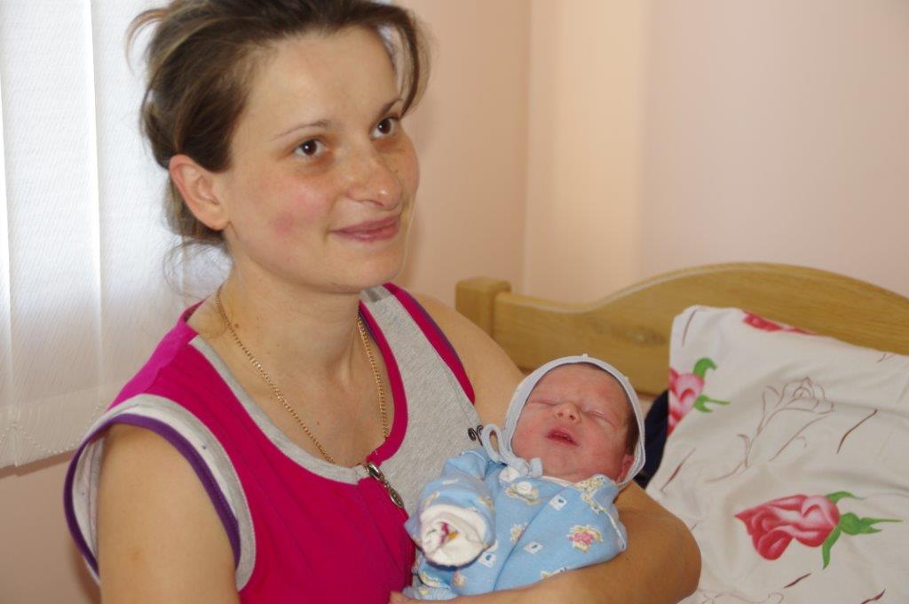Toute souriante, une mère tient son nouveau-né dans les bras.