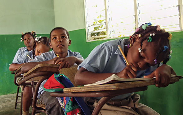 Three girls and a boy sitting in a classroom.